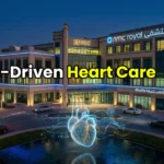 Futuristic exterior of NMC Royal Hospital Abu Dhabi at night featuring a glowing AI heart hologram.